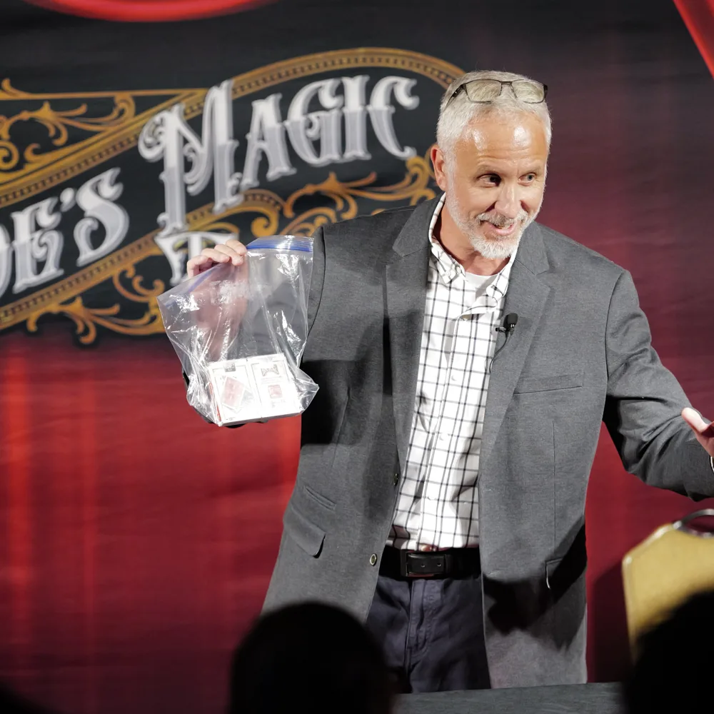 Mike Stringer holding up a clear bag on stage under the Poe's Magic Theatre sign